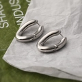 Minimalist silver oval hoop earrings with polished geometric metal on a textured background - Silver Oval