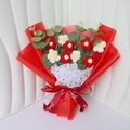 Close-up of handmade crochet flower bouquet with red yarn blossoms and eucalyptus leaves - Red
