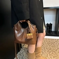 Detalle de bolso tote vintage de cuero marrón con mini accesorio llevado por una modelo - Marrón