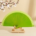 Minimalist solid wood folding fan in vibrant green finish with bamboo stand - Fruit Green