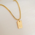 Macro detail of gold-plated rectangular pendant featuring an engraved letter R on box chain - Letter R