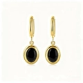 Detailed macro view of vintage gold earrings with oval black stones and zircon accents - Black