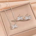 Silver bow-shaped necklace and earrings set with micro-pave crystals on soft beige fabric - Silver X-Shape Jewelry Set