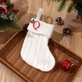 White cable knit Christmas stocking featuring red embroidered letter Q with holly accent - Letter Q
