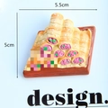 Macro shot of 3D resin crab burger fridge magnet on brown tray with size markings - Taco Cartoon