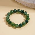 Detailed shot of green acrylic beads with swirl patterns on a textured stone surface - Green