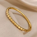 Detailed view of gold Tubogas style flexible bracelet on champagne silk fabric surface - Bamboo Joint Style / Gold