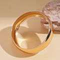 Dettaglio di un bracciale rigido placcato oro lucido con riflesso a specchio su pietra - Bracciale rigido rotondo in metallo dorato
