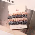 Detail view of four-piece satin scrunchies set in pink and grey on display card - Ivory and Blue Gray