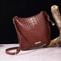 Close-up of deep brown crocodile pattern handbag with golden hardware and textured finish - Brown