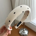 Detail of cream padded satin headband with black polka dots and soft fabric texture - White