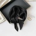 Close-up of a black pleated silk scarf on a sleek black tray with an elegant quote card - 70*70cm / Pleated Black