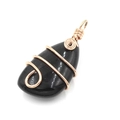 Detail of a black teardrop stone pendant with rose gold wire wrap and spiral bail - Obsidian