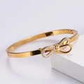 Dettaglio macro del bracciale a fiocco dorato con piccoli cristalli su base bianca - Oro