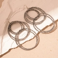 Close-up of layered interlocking dark grey bead hoop earrings on white plaster stone - Silver Gray