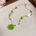 Colorful beaded necklace with green apple pendant on linen background with floral accents - Colorful Apple Star Teardrop Heart Beaded Necklace