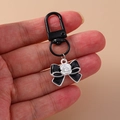Trendy black ribbon keychain with white rose detail and secure black metal hook - Bow