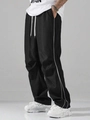 Detail of black sports trousers with white side stripes and wide-leg loose fit - Black