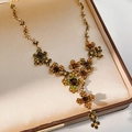Macro shot of a vintage gold floral necklace with amber and green crystals in a jewelry box - Necklace-Gold-Green-Brown
