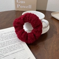 Détail d'un chouchou en polaire teddy bordeaux avec texture peluche sur livre - Rouge Foncé