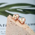Rose gold heart stud earrings with a round yellow stone on a natural beige stone background - Heart 4-Prong Pave / Rose Gold