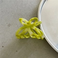 Detail of a yellow translucent acetate hollow flower hair claw on a metal disc - Yellow-Green