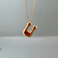Macro view of a polished gold letter U initial pendant on a delicate chain necklace - Letter U Single Pendant