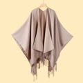 Hellbrauner Strickschal-Poncho mit Fransen auf Holzkleiderbügel vor warmem Hintergrund - Einfarbig Fransen Schultertuch Khaki