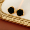 Macro shot of gold square earrings with black velvet inlay on vintage background - Black