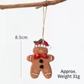 Gingerbread man Christmas tree ornament with red bow tie and hat, hanging on a branch - Santa Hat Gingerbread Man