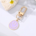 Detailaufnahme von vergoldetem Legierungs-Schlüsselanhänger mit lila Emaille-Smiley-Gesicht - Lila
