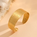 Detail eines breiten goldenen Armreifs mit geprägter Holzmaserung und metallischem Glanz - C-Form Baumrindenstruktur-Stil (R811)