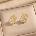 Funkelnde goldfarbene Ohrstecker in B-Form mit Kristallen in einer beigen Schmuckbox - Ohrstecker (263 Goldene Ohrstecker) / Gold