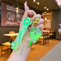 Close-up of green sakura lollipop keychain with liquid glitter sand and gold bell - Green Luminous Bubble Bead Lollipop