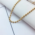 Detailopname van glanzende gouden kogelketting op witte getextureerde achtergrond - Goud