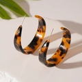 Close-up of C-shaped resin earrings with amber leopard print on a white display stand - Silver Pin Tortoise Leopard Geometric Stud Earrings
