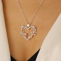 Detail of silver thorn heart necklace with tiny flowers worn on model neck - Shiny Silver Entwined Flower Heart (11638)