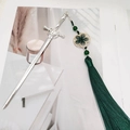 Detail of silver sword hairpin with deep green tassel and decorative beads on a magazine - Sword Tassel-Dark Green