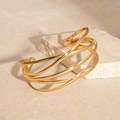 Detailed shot of a layered gold geometric cuff bracelet on a minimalist stone surface - Gold