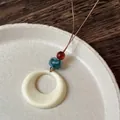 Detailopname van bohemien keramische ketting met blauwe kraal op houten oppervlak - 4# Wit Ring