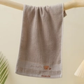 Detail eines weichen Kinderhandtuchs in Hellbraun mit süßer Bärenstickerei und Textur - Bestickter Bärenkopf Braun