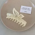 Elegante pinza per capelli a farfalla color crema con design traforato su vassoio - Bianco Sporco