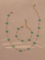 Bohemian jewelry set with turquoise beaded flowers and golden chains on a textured surface - Teal Necklace And Bracelet
