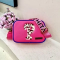 Detailed close-up of pink shoulder bag featuring blue trim and a branded logo plaque - Rose Red