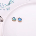 Golden lace pendant with turquoise faceted crystal and blue stone inlay on a ceramic plate - Teal