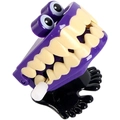 Purple wind-up chattering teeth toy with big eyes and black feet on white background - Ghost Teeth with Eyes
