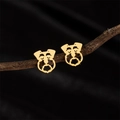 Nahaufnahme goldener Hunde-Ohrstecker mit hohlen Details auf einem rustikalen Zweig - Schnauzer / Gold
