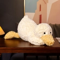 Lying plush duck toy in cream white with yellow beak on a wooden table interior - Lying Duck / 35cm