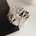Close-up of silver metal heart-shaped link bracelet with hammered texture details - Silver