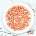 Macro shot of orange ceramic fish beads for handmade DIY bracelets and crafts - Orange Red